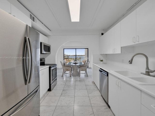 kitchen with white cabinets, appliances with stainless steel finishes, light countertops, and a sink