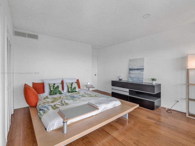 bedroom featuring wood finished floors and visible vents