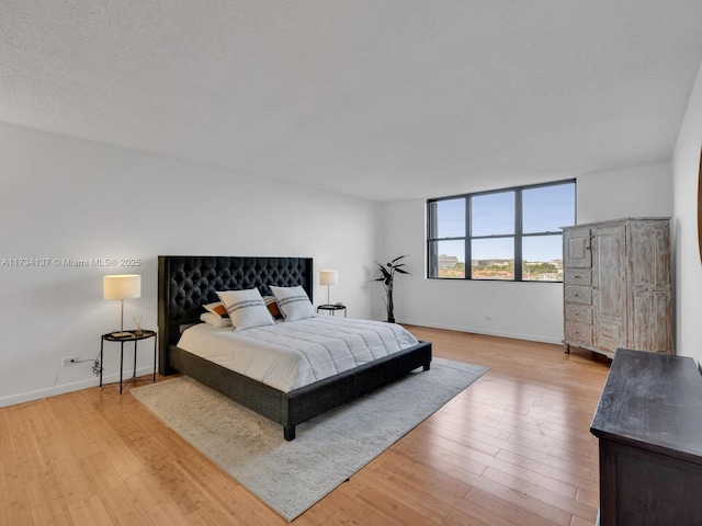 bedroom featuring wood finished floors, baseboards, and a textured ceiling