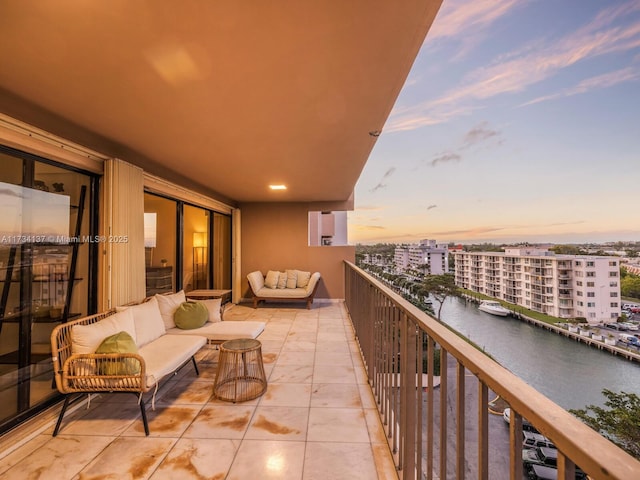 balcony featuring an outdoor living space, a water view, and a city view