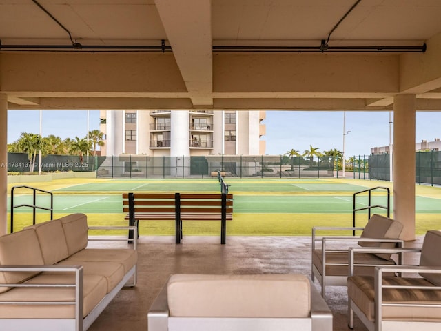 view of home's community with a tennis court, fence, and an outdoor hangout area