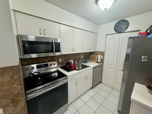 kitchen with sink, stainless steel appliances, white cabinets, a textured ceiling, and decorative backsplash