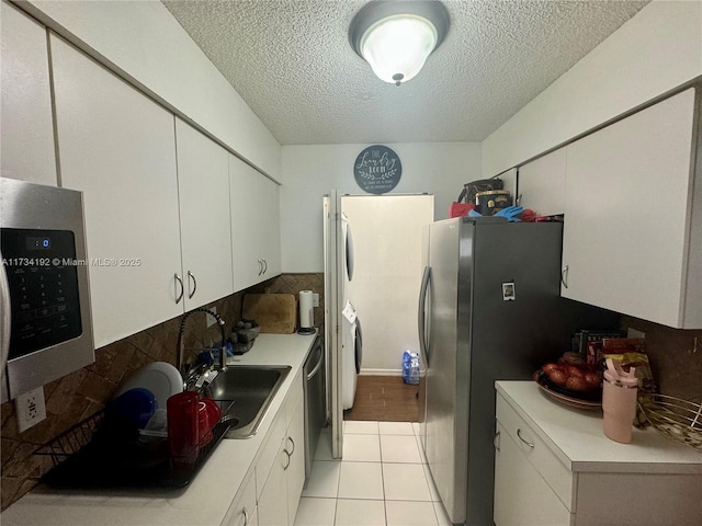 kitchen featuring white cabinetry, stainless steel appliances, light tile patterned flooring, and sink