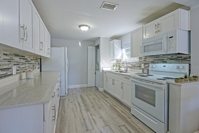 kitchen with sink, white appliances, light stone countertops, light hardwood / wood-style floors, and white cabinets