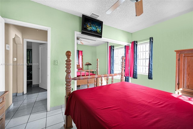 tiled bedroom with ceiling fan and a textured ceiling