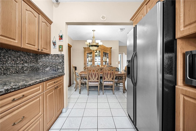 kitchen featuring stainless steel fridge with ice dispenser, decorative backsplash, dark stone counters, and light tile patterned flooring