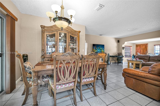 dining space featuring an inviting chandelier, a textured ceiling, and light tile patterned flooring