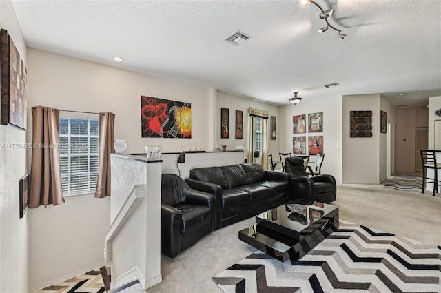 living room with rail lighting, light carpet, and a textured ceiling