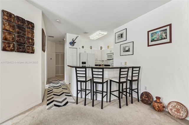 interior space featuring white cabinetry, white appliances, and light carpet