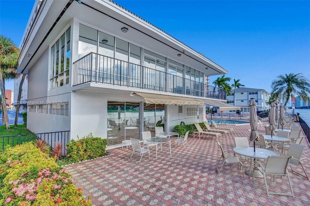 view of patio featuring a community pool and a balcony