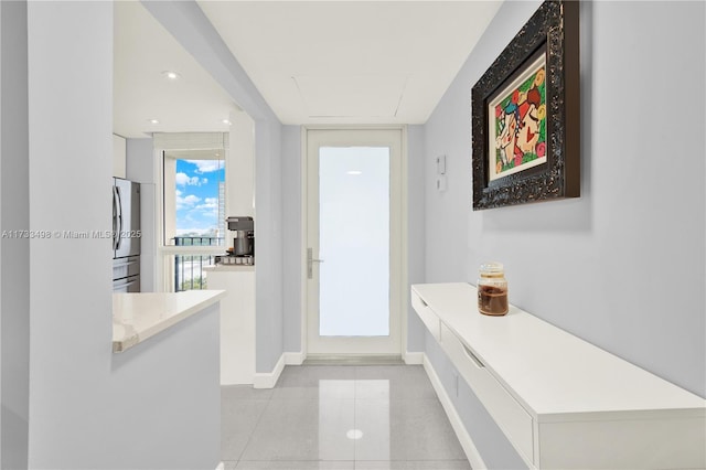 hallway with light tile patterned floors and a wall of windows