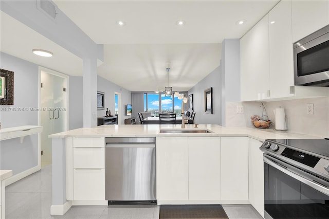 kitchen featuring white cabinetry, appliances with stainless steel finishes, sink, and kitchen peninsula