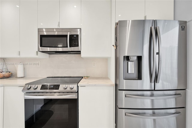 kitchen with light stone counters, appliances with stainless steel finishes, decorative backsplash, and white cabinets