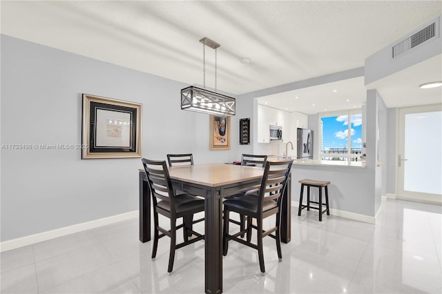 tiled dining area featuring sink and a textured ceiling