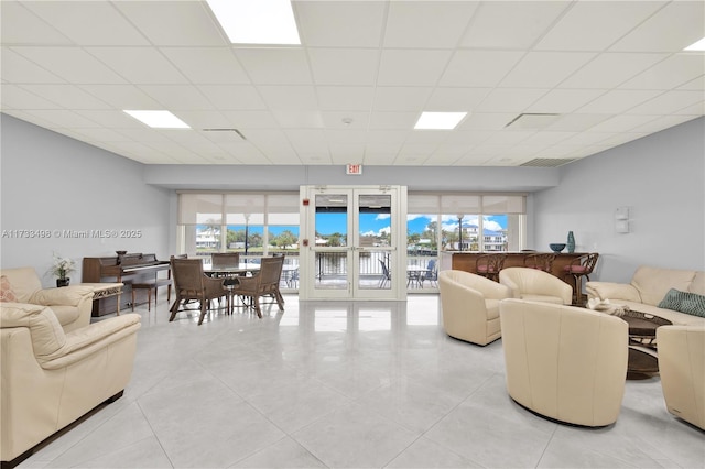 tiled living room featuring a paneled ceiling, french doors, and a healthy amount of sunlight