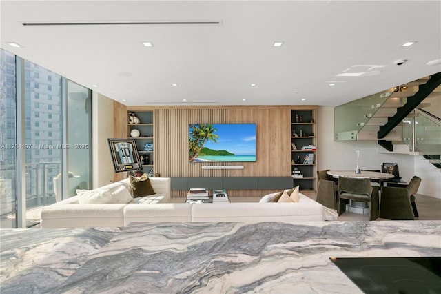 living room featuring built in shelves, expansive windows, and wood walls