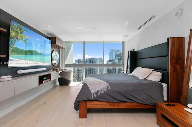 bedroom with a wall of windows and light wood-type flooring