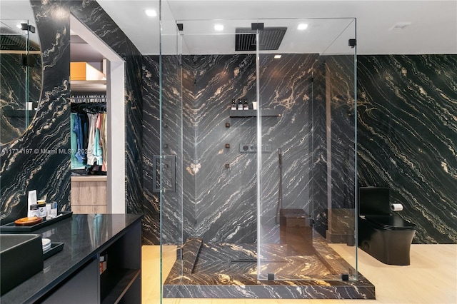 bathroom featuring walk in shower, tile walls, vanity, and toilet