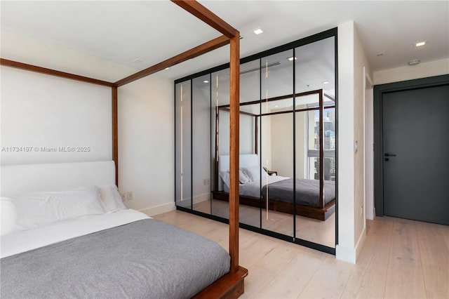 bedroom with expansive windows and light wood-type flooring