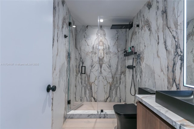 bathroom with vanity, a shower with shower door, tile walls, and toilet