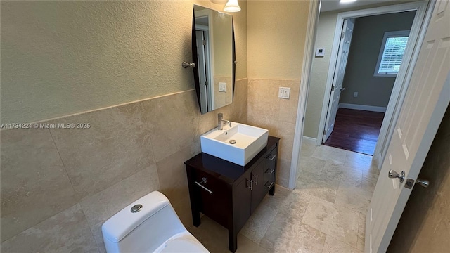 bathroom with vanity, toilet, and tile walls