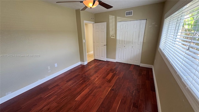 unfurnished bedroom with dark hardwood / wood-style floors, ceiling fan, and a closet