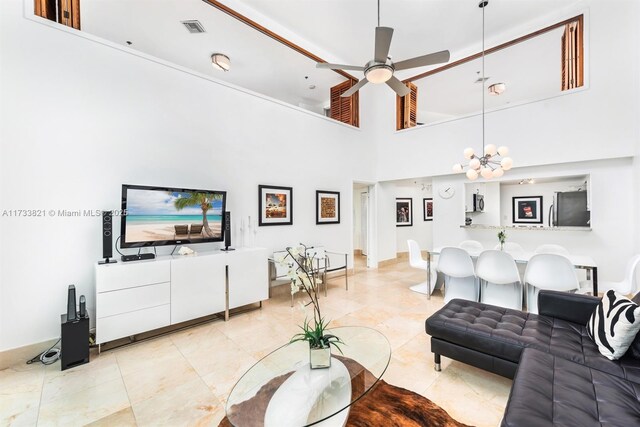 living room with a towering ceiling and ceiling fan with notable chandelier