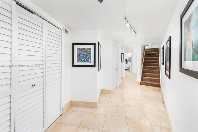 corridor featuring light tile patterned floors and rail lighting