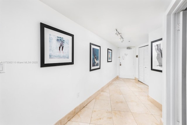 5445 Collins Ave Unit M15, Miami Beach, FL 33140 - hallway with light tile patterned floors, baseboards, and track lighting