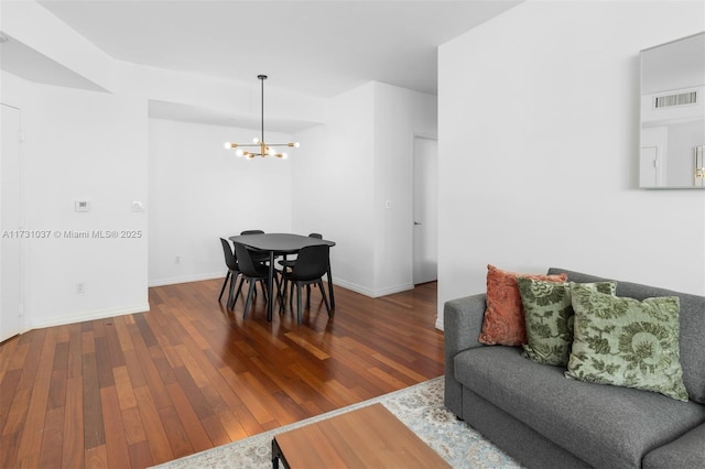 dining area with hardwood / wood-style floors and a notable chandelier