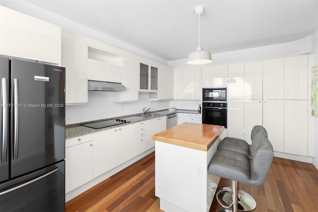 kitchen with white cabinetry, a center island, hanging light fixtures, and black appliances