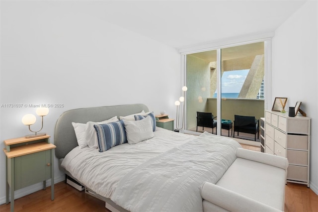 bedroom featuring a wall of windows, access to outside, and light wood-type flooring