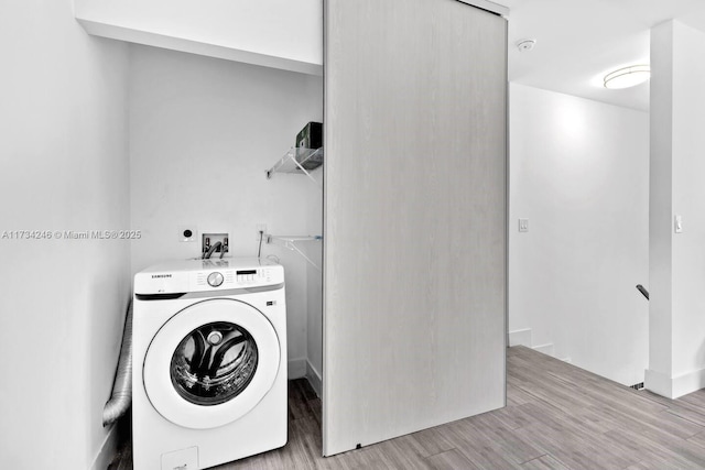 clothes washing area with washer / dryer and light hardwood / wood-style flooring