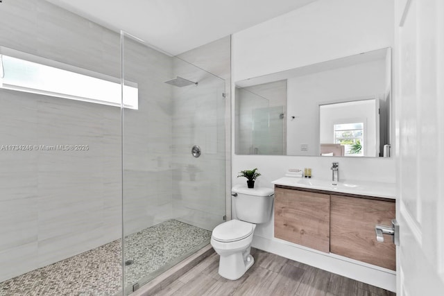 bathroom with tiled shower, vanity, and toilet