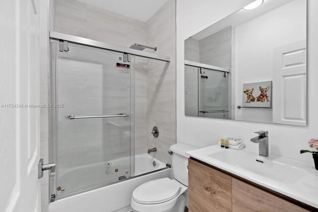 full bathroom with toilet, vanity, and bath / shower combo with glass door