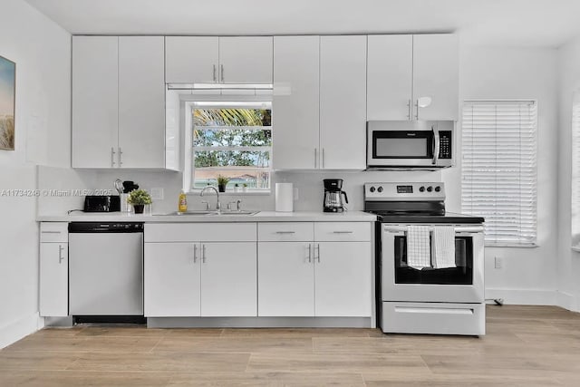 kitchen with white cabinetry, sink, light hardwood / wood-style flooring, and appliances with stainless steel finishes