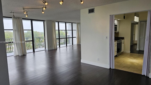 empty room featuring expansive windows, dark hardwood / wood-style flooring, and a textured ceiling