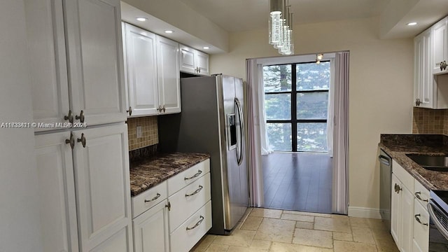 kitchen with dark stone countertops, appliances with stainless steel finishes, pendant lighting, decorative backsplash, and white cabinets