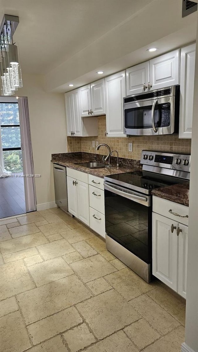 kitchen with sink, appliances with stainless steel finishes, white cabinetry, hanging light fixtures, and tasteful backsplash