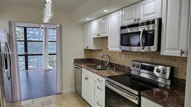 kitchen featuring white cabinetry, stainless steel appliances, sink, and hanging light fixtures