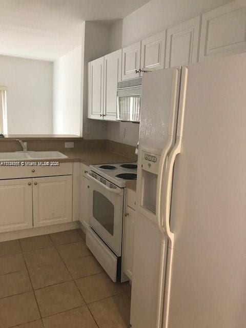 kitchen with sink, white appliances, white cabinets, and tile patterned flooring