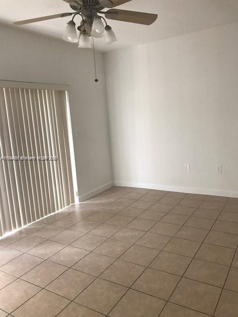 tiled spare room featuring ceiling fan