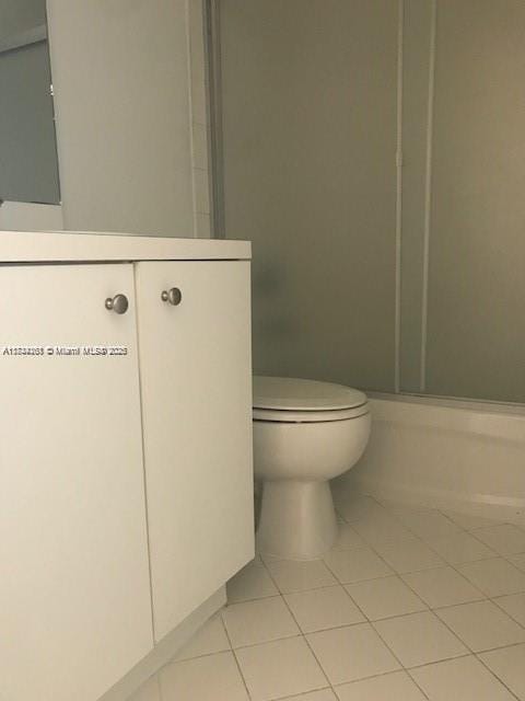 bathroom with tile patterned floors, toilet, a shower with door, and vanity