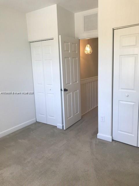 unfurnished bedroom with dark carpet and a closet