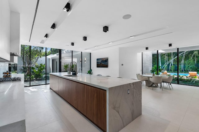 4040 Kiaora St, Miami, FL 33133 - kitchen with modern cabinets, a wall of windows, a spacious island, light stone countertops, and light tile patterned floors