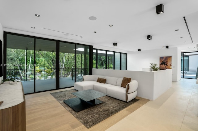 living room with a wealth of natural light, a wall of windows, and light hardwood / wood-style floors