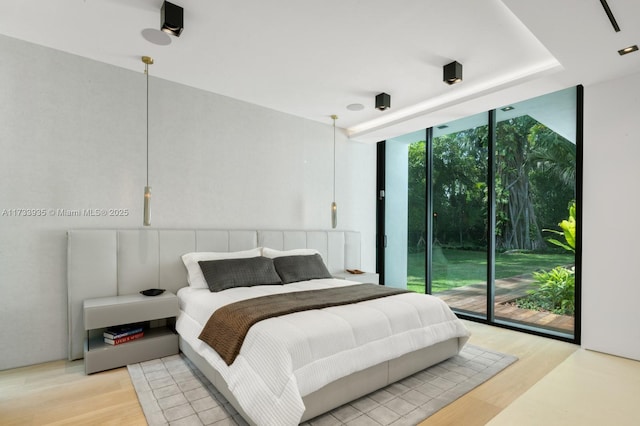 bedroom featuring expansive windows, access to exterior, and light hardwood / wood-style flooring