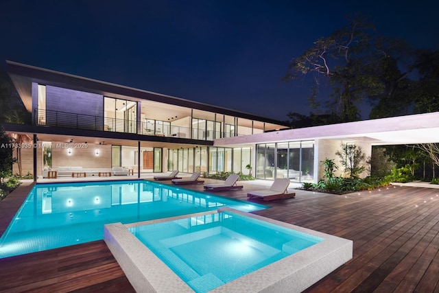 pool at twilight featuring a wooden deck and an in ground hot tub