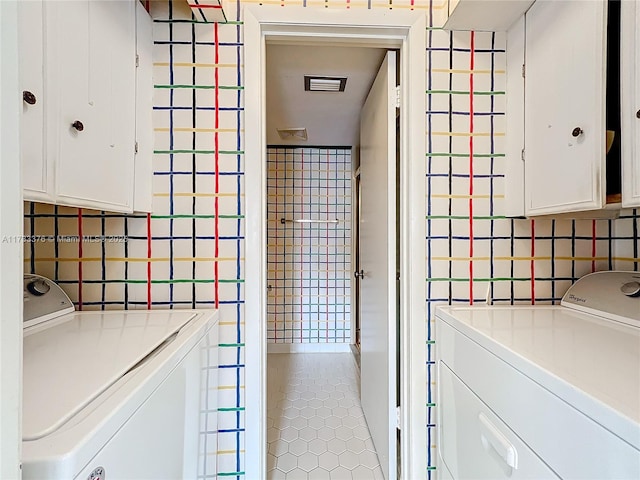 laundry room with cabinets, separate washer and dryer, tile patterned flooring, and tile walls