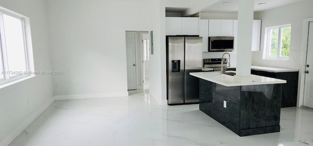 kitchen with a kitchen island with sink, white cabinets, and appliances with stainless steel finishes